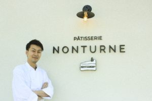 千葉県柏市手賀の杜にオープンしたケーキ屋さんパティスリーノンターンの看板前に立つオーナーシェフの丹野さん