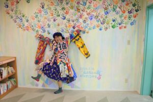 山武市立成東図書館にある自作壁画の前でポーズ。衣装も手作り